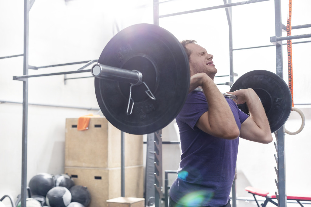 Confident man lifting barbell in crossfit gym